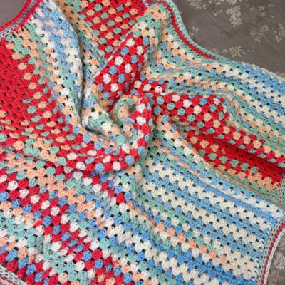colorful light-weight crochet baby blanket on a table