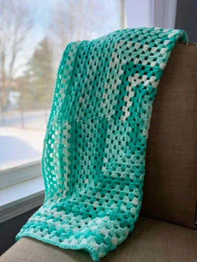 blue and white crocheted baby blanket in granny stitch pattern