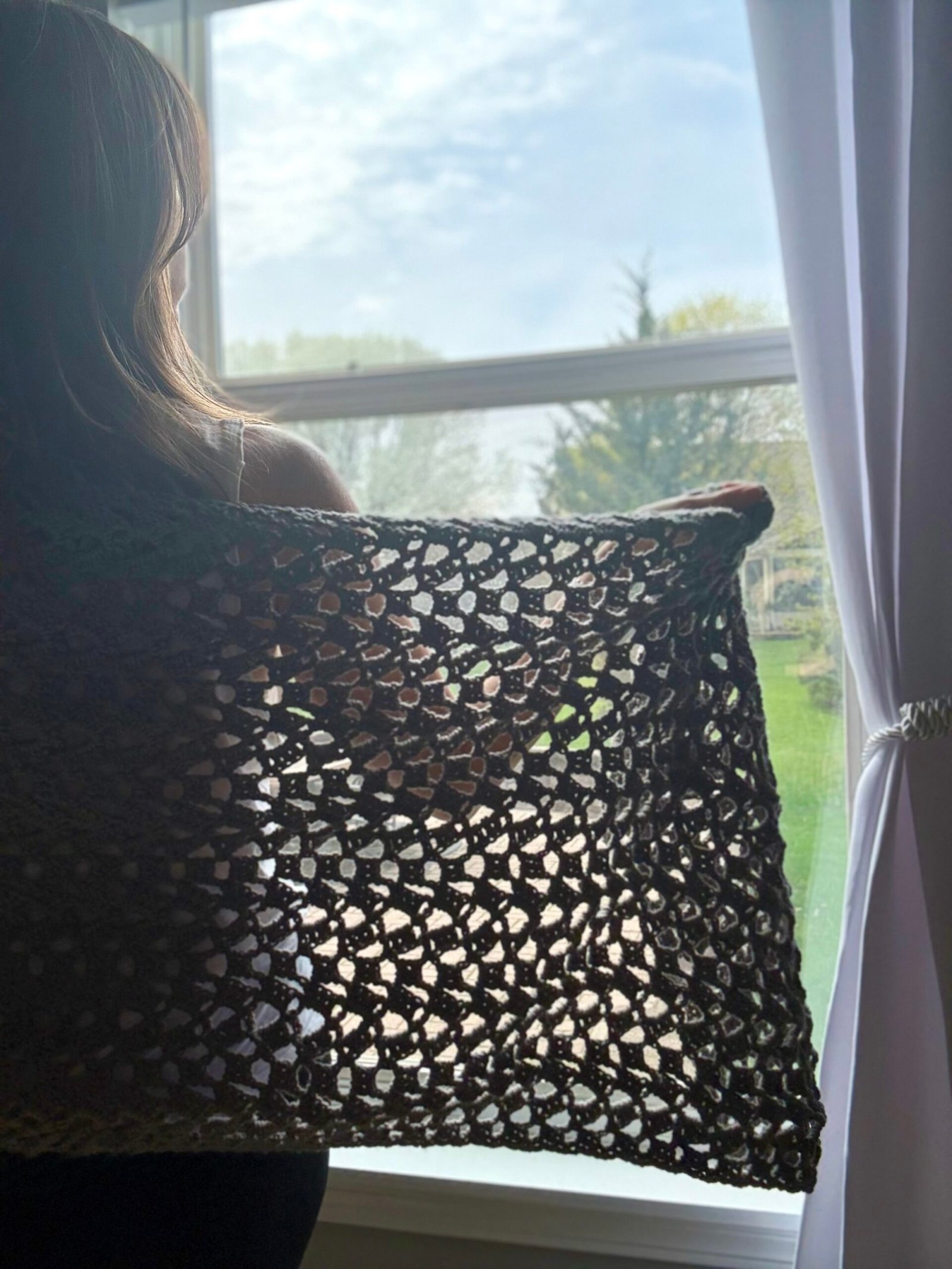 woman wearing crochet wrap in front of a window