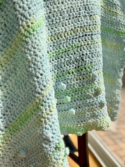 close up of bobble detailing on baby blanket in green and blue