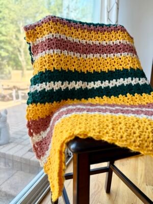 bright chunky crochet blanket over chair in yellow, green, pink and white