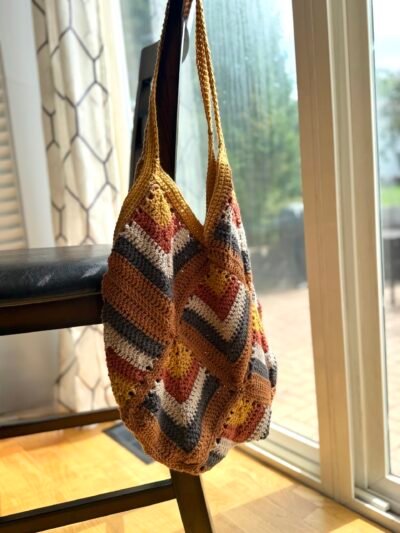 cotton crochet tote in earth colored tones hanging on chair