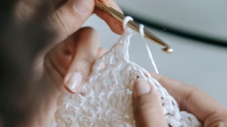 Detailed shot of hands skillfully knitting with a crochet hook and white yarn.