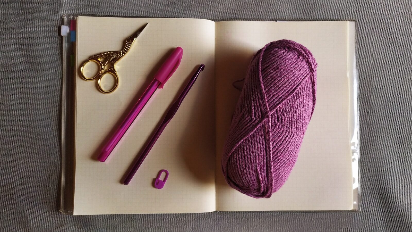purple yarn beside silver scissors and other crochet tools