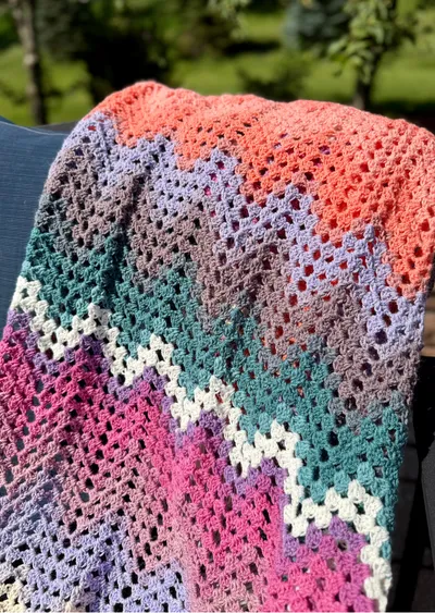 Dragonfly Fields Chevron Blanket PLP v1 multicolored dragonfly fields chevron crochet blanket outside laying on chair